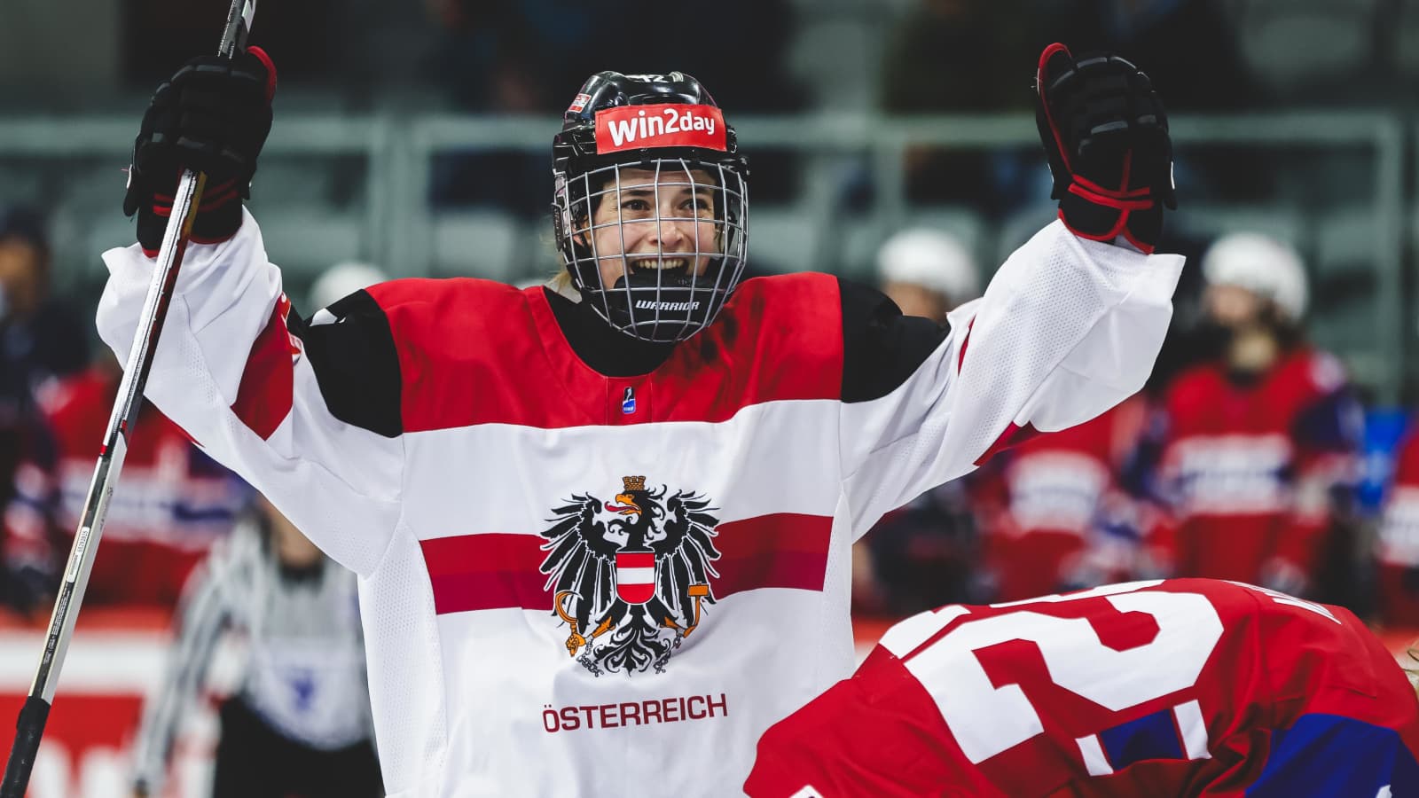 Spielerin der österreichischen Frauen-Nationalmannschaft im Eishockey-Trikot bejubelt einen Moment auf dem Eis.