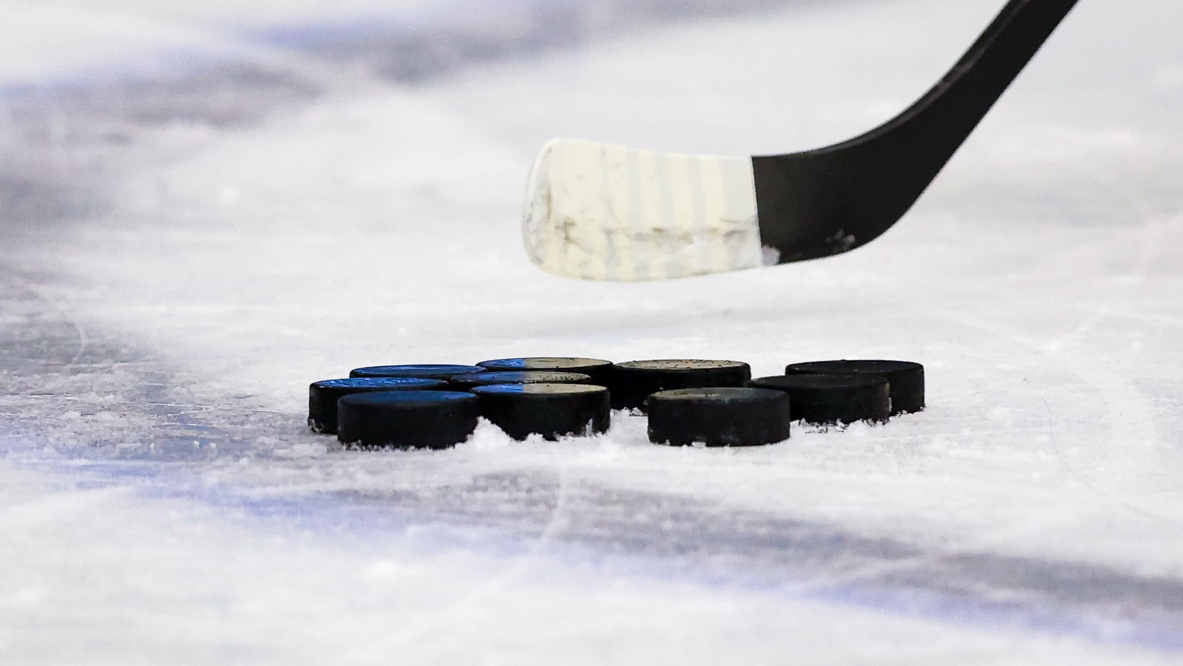 Ein Eishockeyschläger, darunter mehrere Pucks